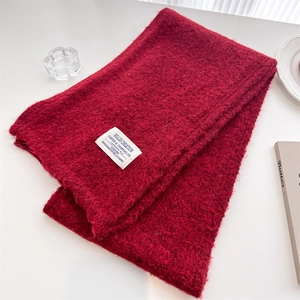 Close-up of thick dark red wool knit scarf texture with stitched white brand label