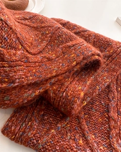 Close-up of caramel orange wool knit scarf with soft plush texture and cable weave pattern