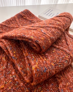 Close-up of orange cable knit wool scarf with colorful flecks and warm thick texture