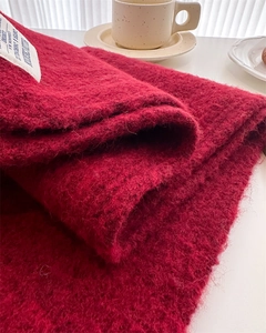 Detail of soft dark red wool knit scarf texture with a vintage woven brand label