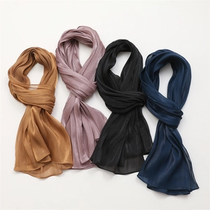 Detailed view of semi-transparent pleated scarves in gold, pink, black and navy blue