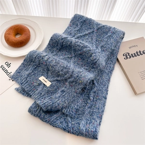 Detail of blue cable knit wool scarf with colorful speckles and woven brand label