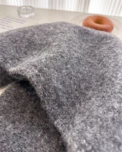 Macro view showing the soft wool texture and thick knit fabric of the charcoal grey scarf