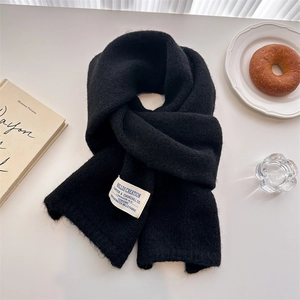 Detail of black wool knit scarf with a decorative tag in a warm winter setting