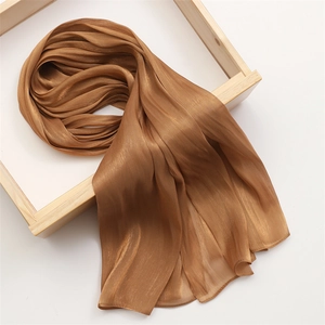 Detail of the bronze silk scarf texture showing glossy finish and fine hemmed edges