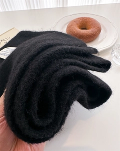 Detailed texture of thick black mohair knit scarf showing soft fluffy fibers and warm weave