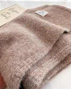 Close-up of brown mohair wool scarf showing fuzzy knit texture and white fabric label