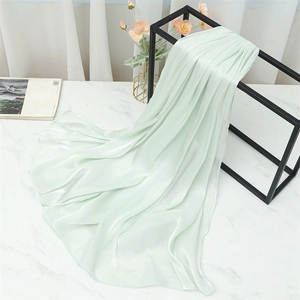 Detailed texture of light green silk scarf showing shiny pleated fabric on display