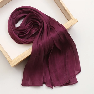 Detail of dark purple pleated cotton linen scarf with soft texture in wooden tray