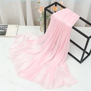 Detail view of light pink silk shawl hanging on a sleek metal rack with floral decor
