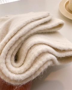 Close-up of soft fluffy texture on a cream wool knitted scarf showing material detail