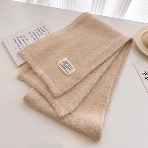 Detailed macro view of the soft beige wool knit texture and minimalist brand label