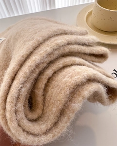 Close-up of thick beige wool knit scarf showing soft texture and fluffy quality