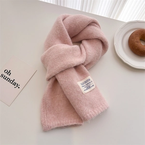 Close-up of pink wool knit scarf with brand label and elegant table setting
