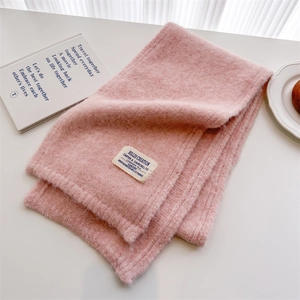 Detail of pink wool knit scarf with brand label on a white minimalist background