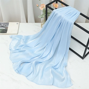 Detail of light blue silk scarf with pearl luster draped on a minimalist black iron stand