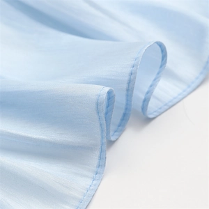 Detail showing ruffle edges and fine stitching on light blue soft linen scarf fabric