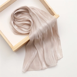 Detail of champagne gold silk scarf showing vertical pleated texture and satin luster