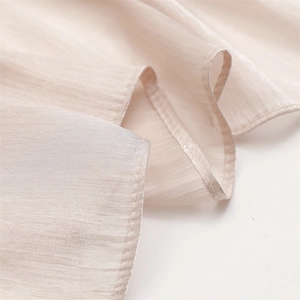 Macro detail of champagne lightweight scarf fabric with fine vertical texture and hem