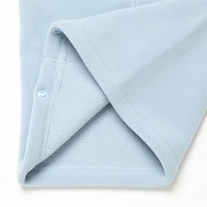 Détail de la texture polaire bleu clair avec fermeture à bouton-pression en plastique