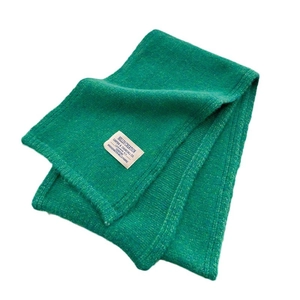 Minimalist grass green knit wool scarf with a woven label on a clean white background