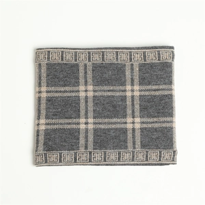 Close-up of thick checkered knit scarf showing grey and cream wool texture and weave