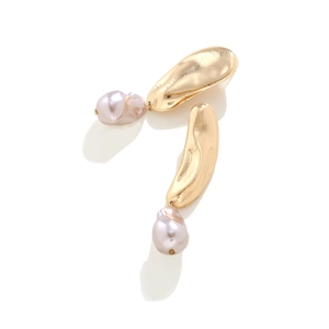 Detail of asymmetrical gold earrings featuring baroque pearls and hammered metal texture