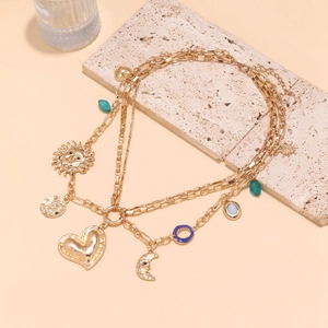 Multilayer gold necklace with sun, moon, and heart charms on a decorative stone base