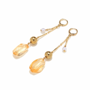 Détail de boucles d'oreilles dorées avec pendentifs géométriques en résine jaune