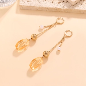 Détail de pendentifs géométriques en résine ambre sur boucles d'oreilles dorées