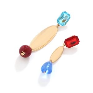 Détail de boucles d'oreilles asymétriques en métal doré mat et pierres de résine colorées