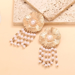 Macro detail of golden flower earrings with pearl tassels and intricate petal texture