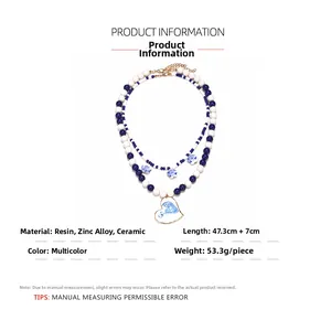 Macro shot of layered blue and white beaded necklace with ceramic heart pendant detail