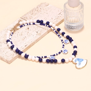 Detail view of multi-layer beaded necklace featuring porcelain heart pendant with blue texture
