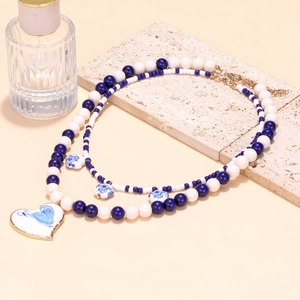Close-up of double-layer beaded necklace with blue and white porcelain heart pendant
