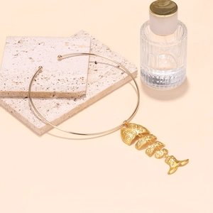 Close-up of golden fishbone pendant on a sleek collar with detailed spiral texture