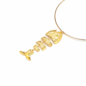 Macro detail of golden alloy fish bone pendant with embossed patterns and jointed structure