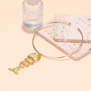 Minimalist gold alloy fishbone pendant necklace displayed on a textured stone surface