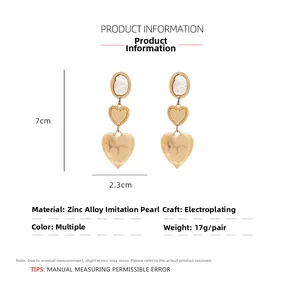 Detail view of gold heart layered earrings with pearl studs and size measurements