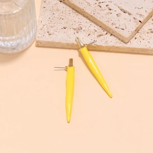 Gros plan détaillé des boucles d'oreilles piment jaune sur texture de pierre