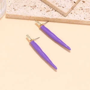 Détail macro de longues boucles d'oreilles piment en émail violet avec capuchons dorés chic