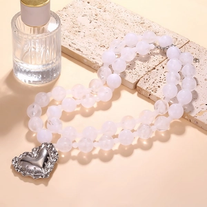 Collier à double rangée de perles avec pendentif cœur argenté sur fond de pierre