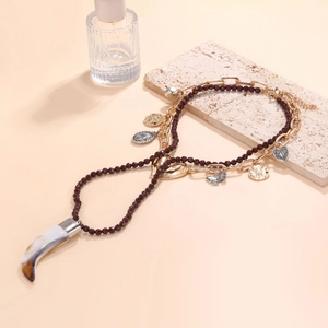 Detail of layered bohemian necklace with red beads, gold charms, and marble tusk pendant