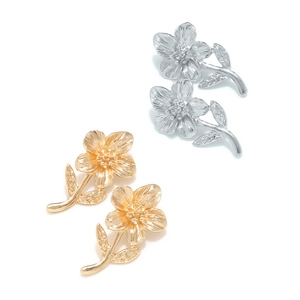 Close-up of gold and silver flower earrings with detailed petal and leaf textures