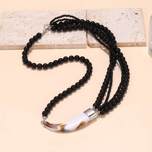 Multi-strand black beaded necklace with a marbled horn pendant in a bohemian style