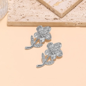 Detailed close-up of textured alloy flower earrings with brushed metallic finish