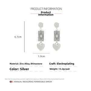 Detailed view of long silver heart dangle earrings with dimensions 6.7cm by 1.9cm