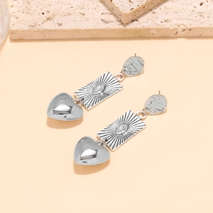 Close-up of vintage silver tiered earrings featuring textured discs and heart pendants