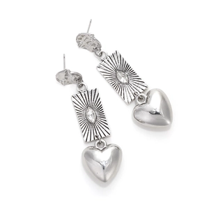 Detail of silver layered earrings featuring coin charms and polished heart pendants