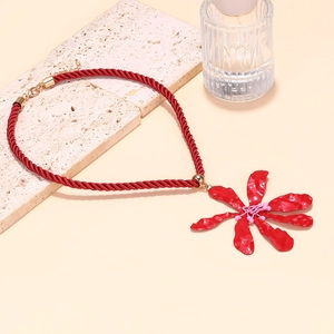 Macro detail of large red flower pendant necklace with silk cord and golden clasp
